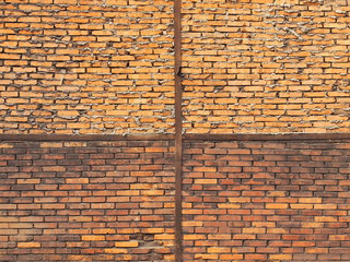 Weathered brick wall divided into four quarters by a metal construction.
