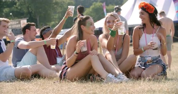 Friends sitting on grass watching a gig at a music festival