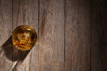 Glass of whiskey with ice on wood