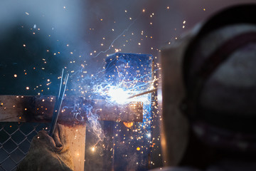 Arc welder worker in protective mask welding metal construction - obrazy, fototapety, plakaty