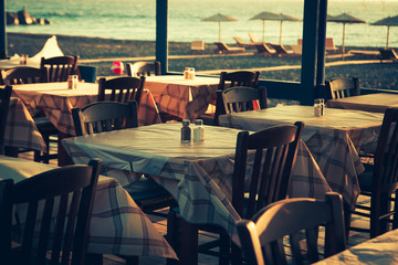 traditional greek outdoor restaurant on terrace overlooking Mediterranean sea (Greece ).  toned image
