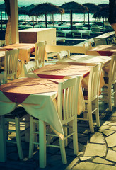 traditional greek outdoor restaurant on terrace overlooking Mediterranean sea (Greece ).  toned image