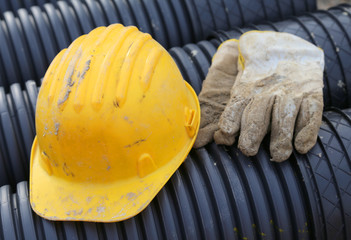 yellow hard hat and work gloves in construction site