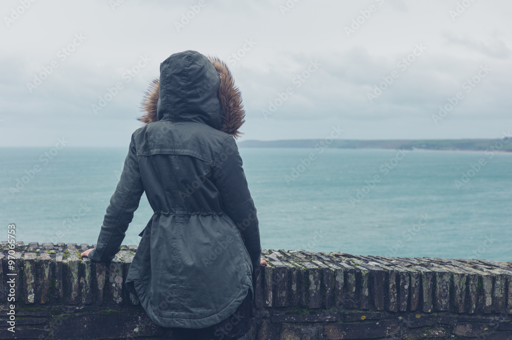 Poster Person in winter coat by the sea