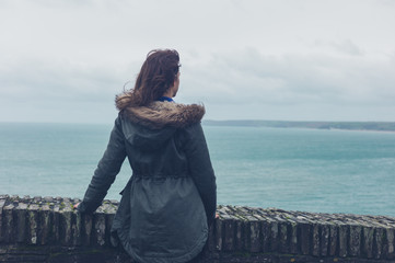 Young woman in winter coat by the sea © LoloStock