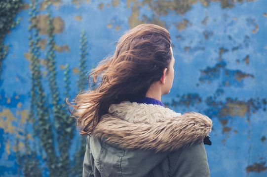 Young woman by blue wall on windy day