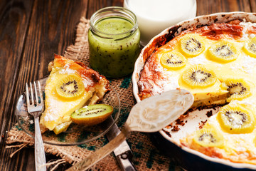 
home baked pie with kiwi, milk and jam on a wooden background