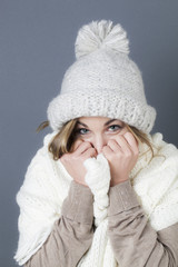 trendy warm winter - lovely young blond girl wearing white wool winter hat and scarf smiling for softness and cozy fashion