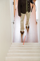 Blind woman using a walking stick on stairway