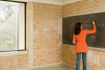 Teacher writing Spanish text on blackboard