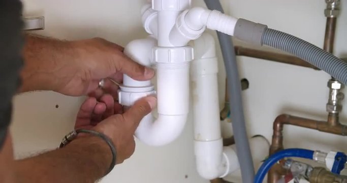 Male plumber fixing a kitchen sink, close-up of hands - Powered by Adobe