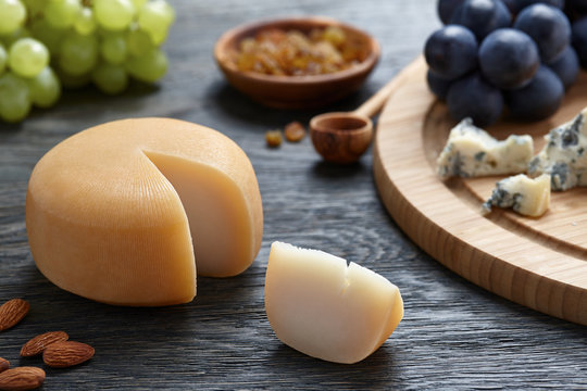 Round cheese with grapes on wooden backround
