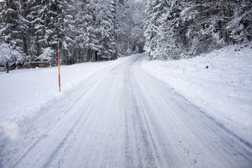 Heavy snowy countryside road. Danderous snowy and icy winter forest plowed road background. 