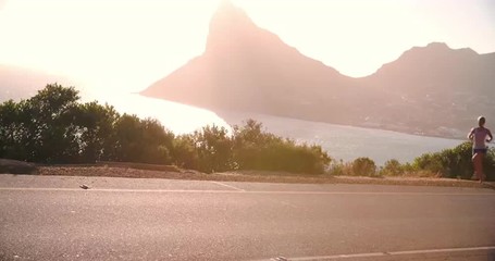 Man and woman running together on an empty coastal road