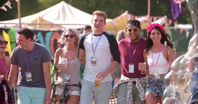 Group of friends walking at a music festival, slow motion