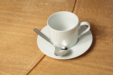 Empty white cup and saucer on wooden background