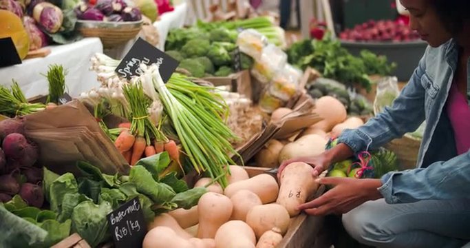 Young woman buying vegetables at a food market stall