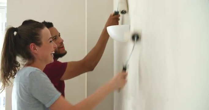 Young couple decorating home with paint rollers, close up