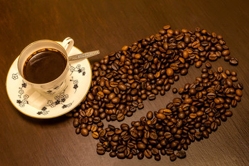 Morning coffee. A cup of coffee and coffee beans like one big bean on the table.