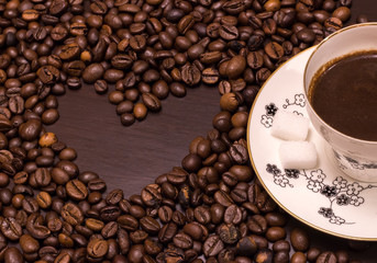 Heart shape made from coffee beans and a cup of coffee.