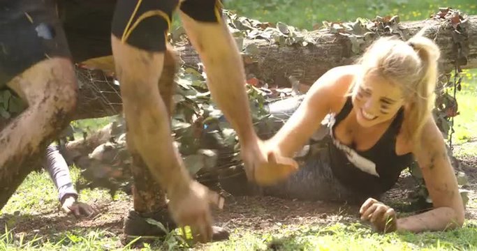 Competitors help each other through net on an assault course