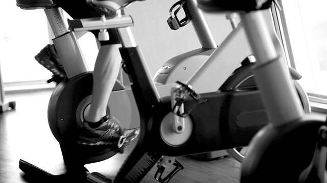 Black and white footage working out on the exercise bike in the gym