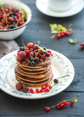 Breakfast set. Buckwheat pancakes with fresh berries and honey on rustic plate over black wooden table