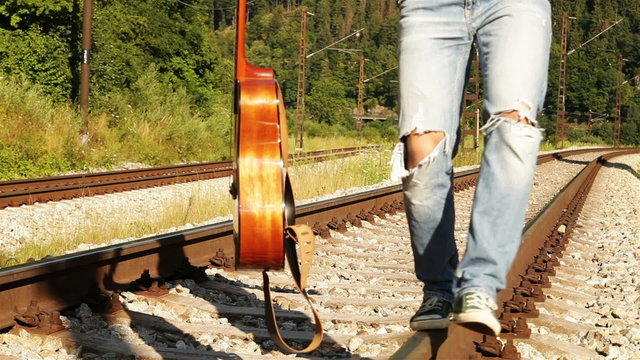A male teenager walks balancing along the railway with the guitar

High Definition Video : 29.97 FPS 10sec 
 Please look another footages on my Train_Arrival Account. 
Best Wishes.