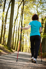 Nordic walking. Woman hiking in the forest park.