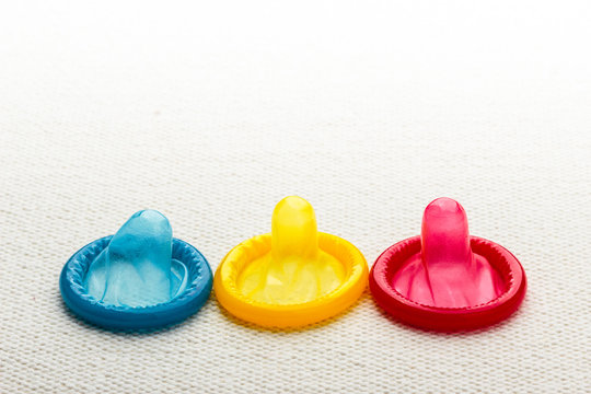 Colorful condoms on white cloth.