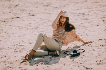 Retro Girl With Camera Sitting On Sand