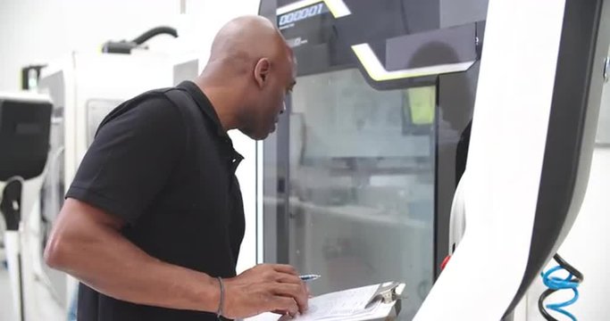 Male Engineer Operating CNC Machinery On Factory Floor