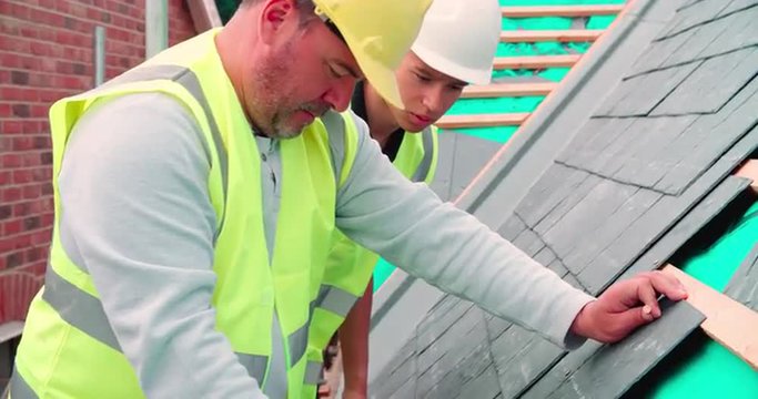 Construction Worker With Apprentice Laying Slate Tiles 