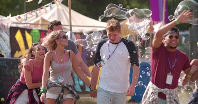 Friends walk through bubbles at music festival, slow motion