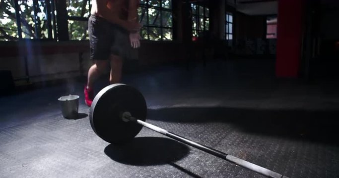 Bare chested man weightlifting barbells in a gym