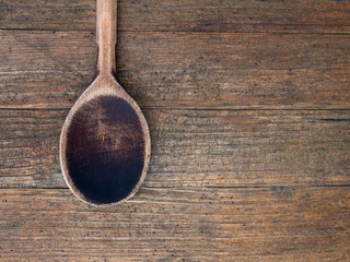 Old, used and worn. Wooden spoon on rustic wood background.