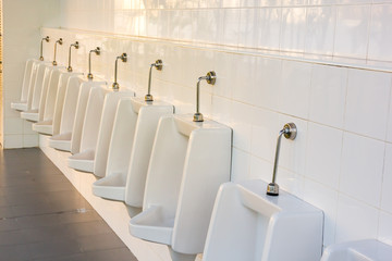 line of white porcelain urinals in public toilets