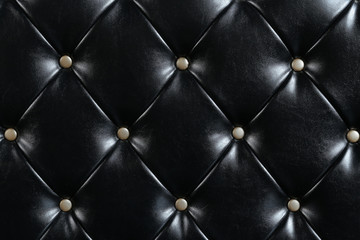 Naklejka premium Black leather upholstery with gold buttons