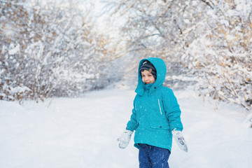 Fototapeta na wymiar A cute little boy stands in winter forest