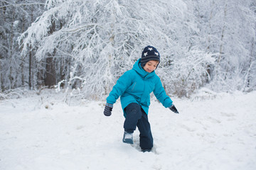 Fototapeta na wymiar A little boy walks in a snow in the winter park
