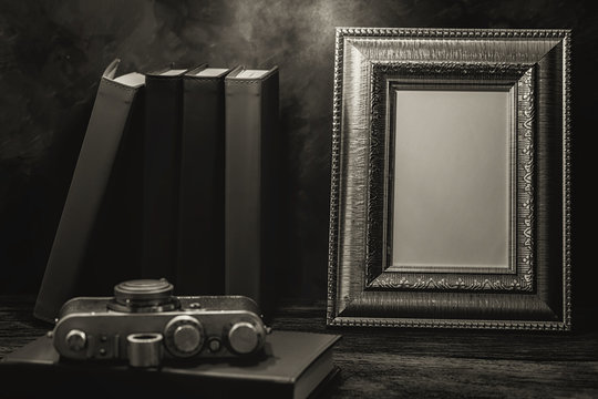Still life of picture frame on table with vintage camera