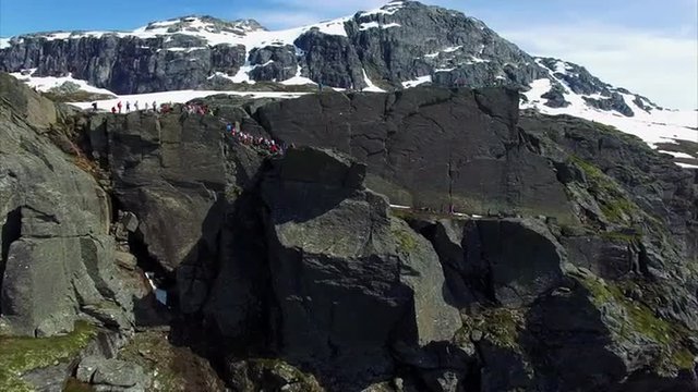 Aerial footage of popular Trolltunga rock in Norway with crowds of people queueing to make a photograph, one of the main tourist sites in Norway. Aerial 4k Ultra HD.
