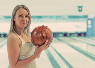 Fototapeta premium Pretty woman holding ball in bowling club.