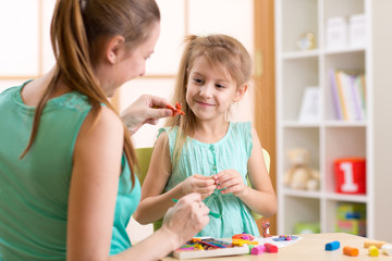 Fototapeta premium kid girl and mother play colorful clay toys at nursery at home