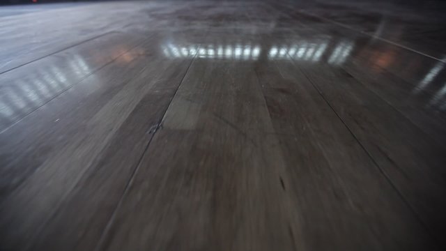 Camera travels on wooden floor of a basketball arena