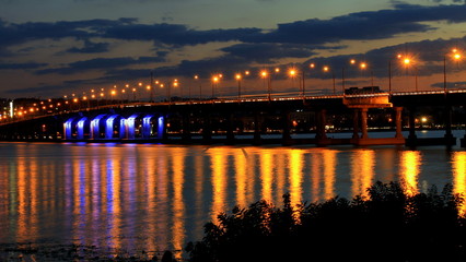 Fototapeta na wymiar Bridge in the evening , lights reflected on the water on the Dnieper river , Dnepropetrovsk, Ukraine .