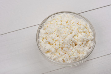 Cottage cheese in bowl on white a wooden surface