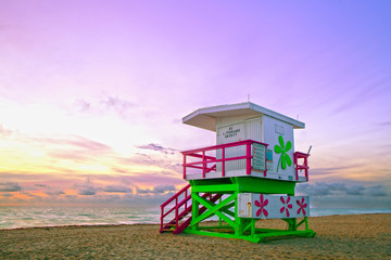 Sunrise in Miami Beach Florida, with a colorful lifeguard house in a typical Art Deco architecture, at sunrise with ocean and sky in the background.