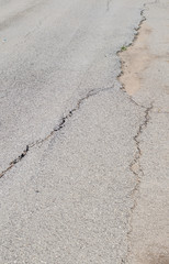 cracked road and potholes in pavement of a city street