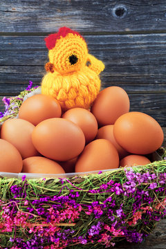 Chicken eggs in a basket and chicken on a wooden background